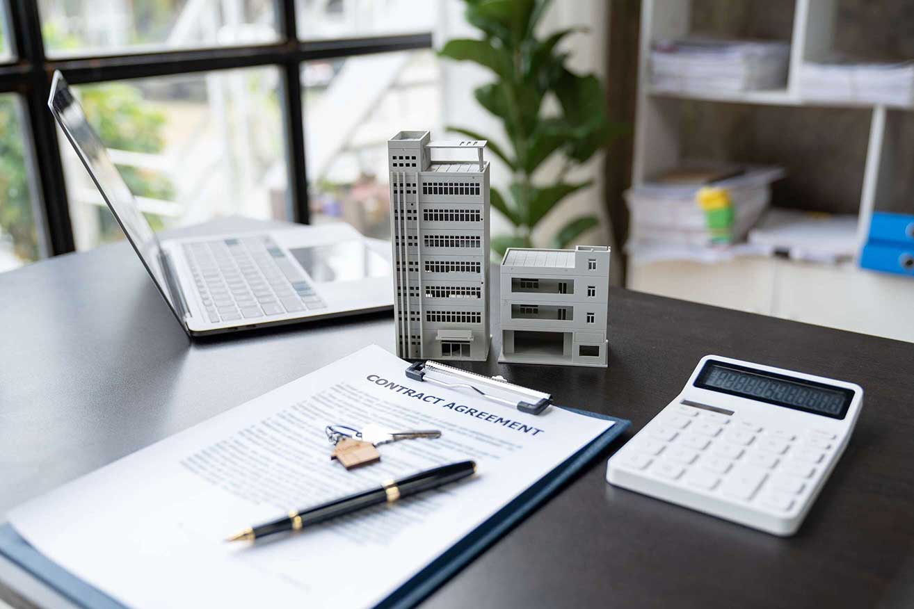 A model of high-rise condominiums next to a contract agreement, symbolizing the investment opportunities in non-warrantable condos.-Non-QM Loans